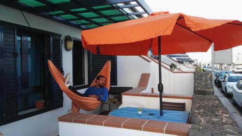 a man sitting in a hammock under an umbrella at Papá Totë in Playa Honda