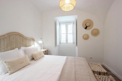 a white bed with white pillows and a window at Lavradores Boutique Guesthouse in Évora