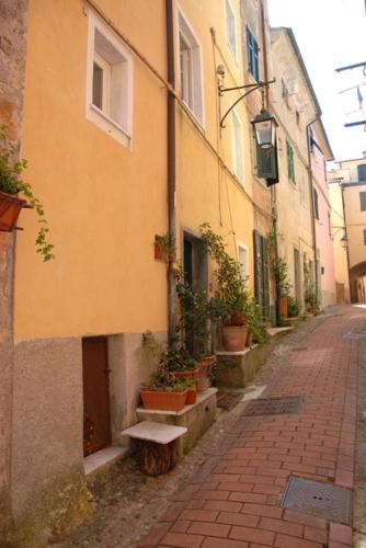 an alley with a yellow building and potted plants at Fivestay Roof terrace overlooking the gulf in Monte Marcello