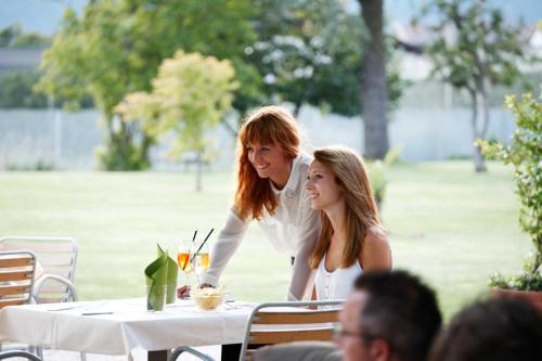 two women sitting at a table in a park at Hotel Raffl in Bolzano