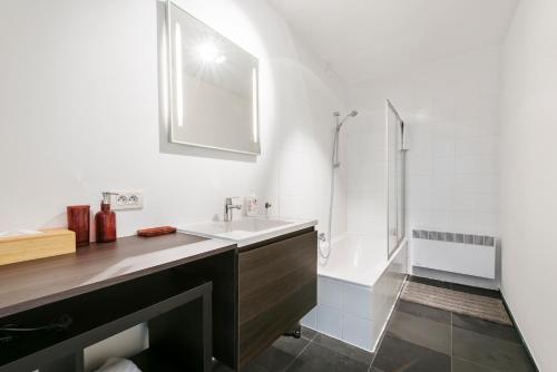 een witte badkamer met een wastafel en een douche bij Classy Apartment in City Center with Large Balcony in Gent