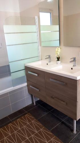 une salle de bain avec deux lavabos et un miroir dans l'établissement Bienvenue à Bordeaux! Parking Pétanque Wi Fi, à Beychac-et-Caillau