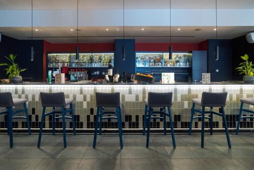 a bar with blue stools in a restaurant at Vienna House Easy by Wyndham Bucharest Airport in Otopeni