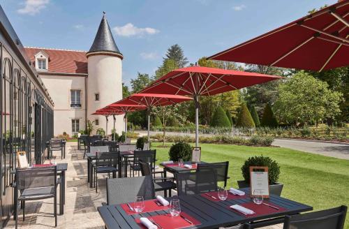 a patio with tables and chairs with red umbrellas at Château Saint-Jean, Relais & Châteaux in Montluçon
