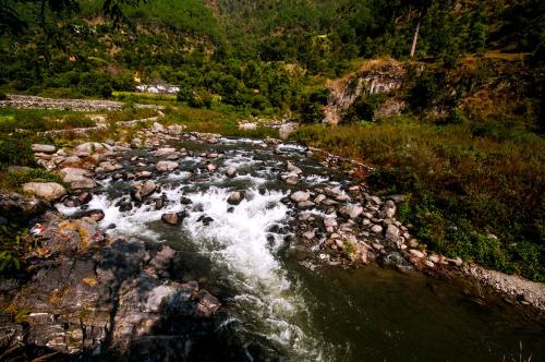 a stream of water with rocks in a river at DreamCatcher By Samyati Hotels and Resorts in Bhīm Tāl