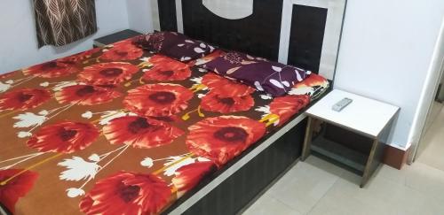 a bed with a floral comforter and a table at Sai Guest House in Pathānkot