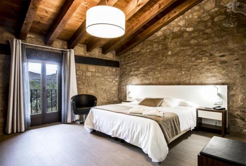 ein Schlafzimmer mit einem großen weißen Bett und einem Stuhl in der Unterkunft Hotel Restaurante Masía la Torre in Mora de Rubielos