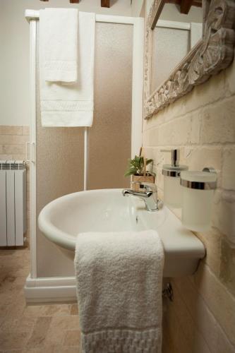 a white bathroom with a sink and a mirror at Antico Granaione in Rapolano Terme