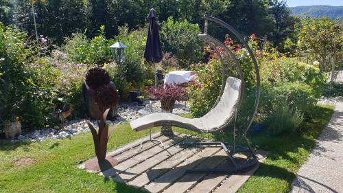 a chair and an umbrella in a garden at Gästehaus Marlies Keutschach am See in Keutschach am See