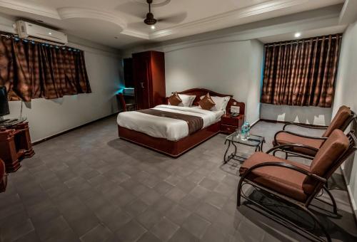 a hotel room with a bed and a couch and chairs at Hotel JMC Group in Rajkot