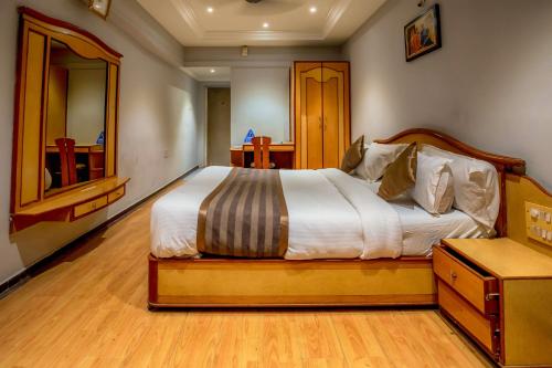 a bedroom with a large bed and a dresser at Hotel JMC Group in Rajkot