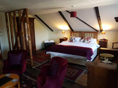 a bedroom with a large bed and two chairs at Oak Tree Farm in Yoxford