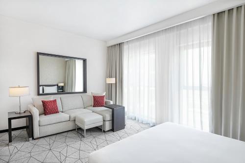 a hotel room with a couch and a mirror at Hyatt Place Dubai Jumeirah in Dubai
