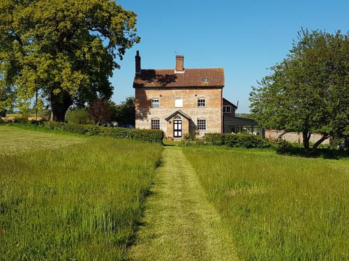 an old house in a field with a dirt road at Oak Tree Farm in Yoxford