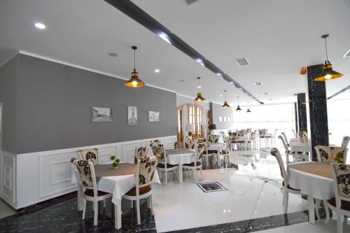 uma sala de jantar com mesas e cadeiras brancas em Monte Mare Hotel em Vlorë