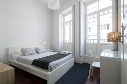a white bedroom with a bed and two windows at Baixa24 · City Center Private Sun Deck Apartment in Porto