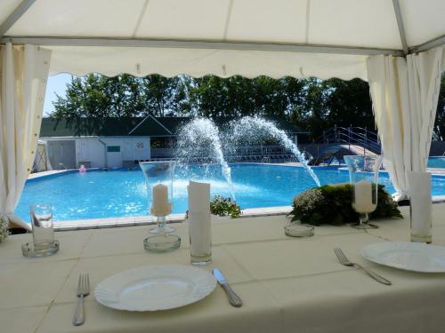 a table with plates and candles in front of a swimming pool at Hotel Vetrenjača in Vršac