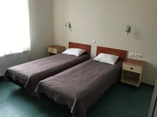 two beds in a room with two tables and a window at Hommiku Guesthouse in Pärnu