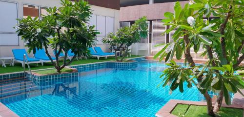 a pool with blue chairs and trees in a building at FuramaXclusive Sathorn, Bangkok in Bangkok