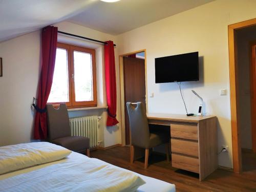 um quarto com uma secretária, uma televisão e uma cama em Hotel Oyer Hof - selbst Service em Oy-Mittelberg