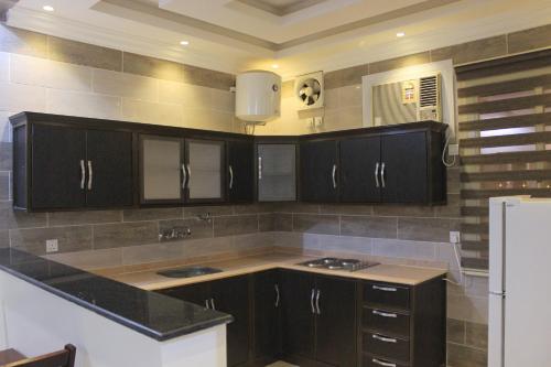uma cozinha com armários pretos e um frigorífico branco em Dar Al Jood Hotel units em Qal'at Bishah