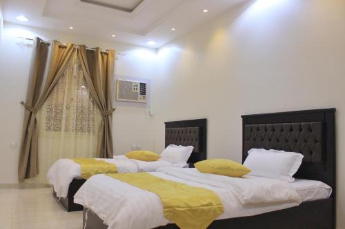 وحدات دار الجود الفندقية في قلعة بيشة: سريرين مع وسائد صفراء في غرفة النوم