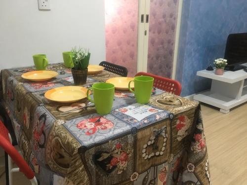 a table with green cups and plates on it at Woodsbury Suites 7722 Butterworth Penang in Butterworth