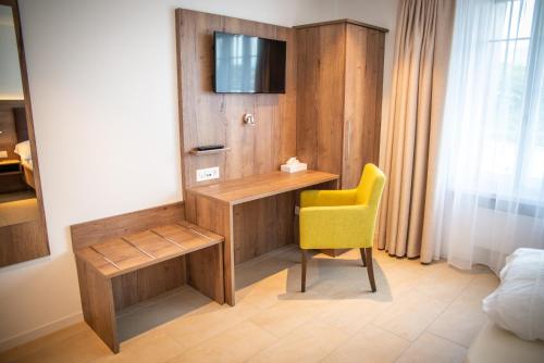 Habitación con escritorio y silla amarilla. en Hotel Schützenhaus, en Uznach