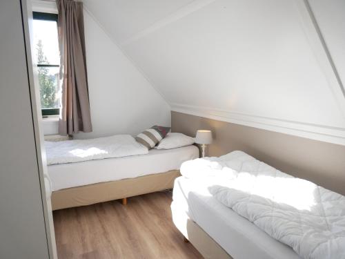 two beds in a small room with a window at Buitenplaats Villa Deluxe in Callantsoog