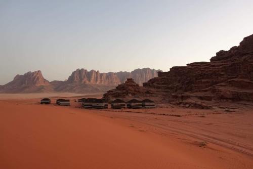 a group of huts in the desert near some rocks at bedouin future camp in Wadi Rum