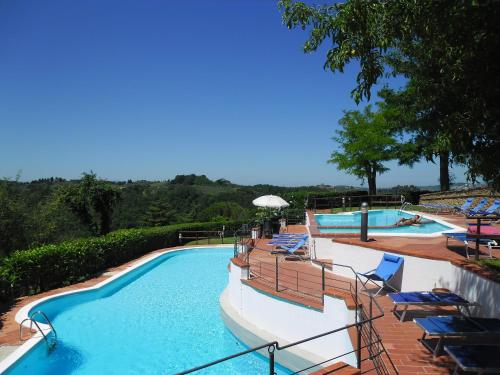 a large swimming pool with chairs and an umbrella at Borgo La Casaccia in Montaione