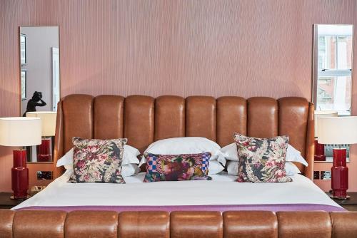 a bed with a brown leather headboard and pillows at Hotel du Vin Birmingham in Birmingham