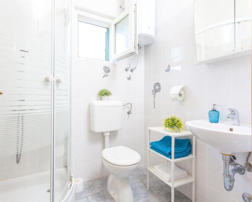 a white bathroom with a toilet and a sink at Kuća za odmor MAJA in Tučepi