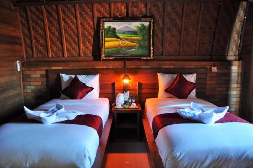 two beds in a room with a painting on the wall at Surya Chandra Beach Bungalow in Nusa Penida