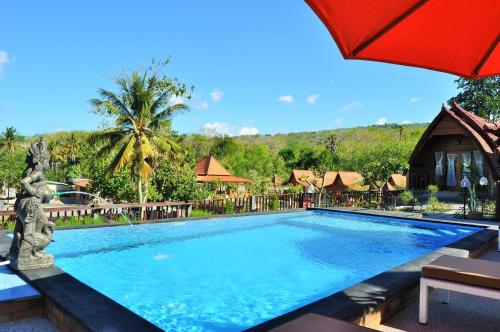 a swimming pool in a resort with an umbrella at Surya Chandra Beach Bungalow in Nusa Penida