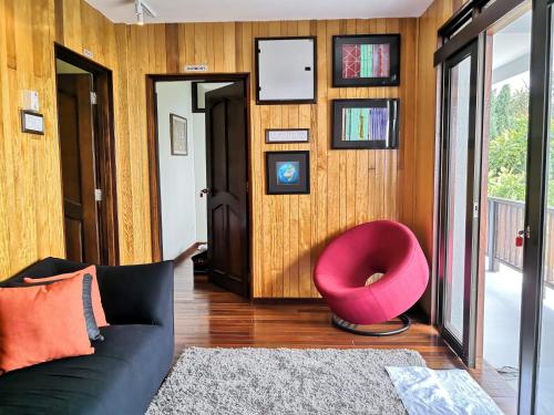 a living room with a black couch and a pink chair at Kairos Villa in Seremban