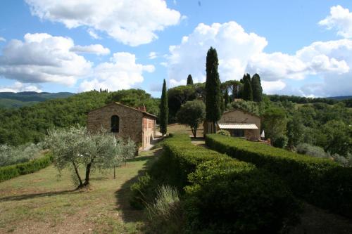 a stone building on a hill with trees and bushes at Podere Capitignano in Borgo San Lorenzo