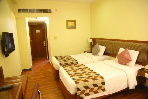 a hotel room with two beds and a television at Royal Fort Hotel in Visakhapatnam