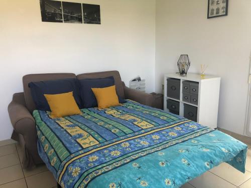 ein Schlafzimmer mit einem Bett mit einer blau-gelben Steppdecke in der Unterkunft Appartement au milieu des lacs, au bord du Guiers in Aoste