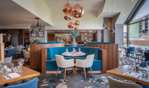 a restaurant with a blue couch and tables and chairs at Clayton Hotel, Manchester Airport in Hale