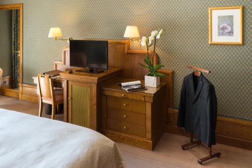 a hotel room with a bed and a desk with a television at Le Grand Hôtel - Domaine De Divonne in Divonne-les-Bains