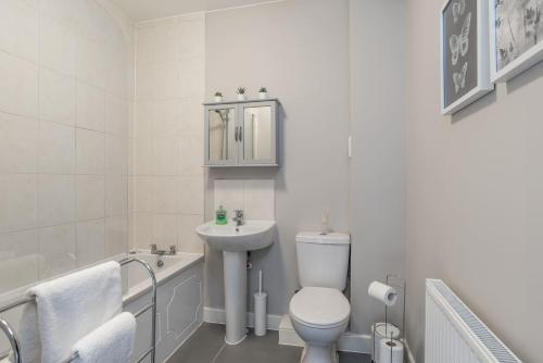 a bathroom with a toilet and a sink and a bath tub at Ashland House in Milton Keynes