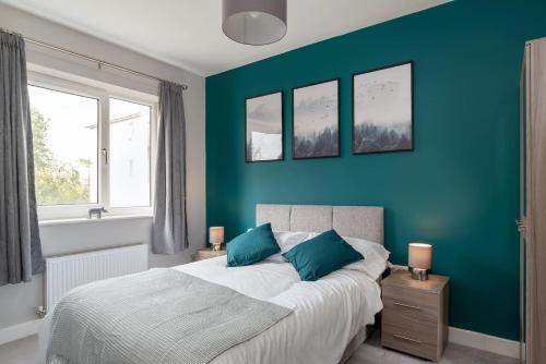 a bedroom with blue walls and a bed with blue pillows at Ashland House in Milton Keynes