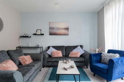 a living room with a gray couch and blue chairs at Ashland House in Milton Keynes