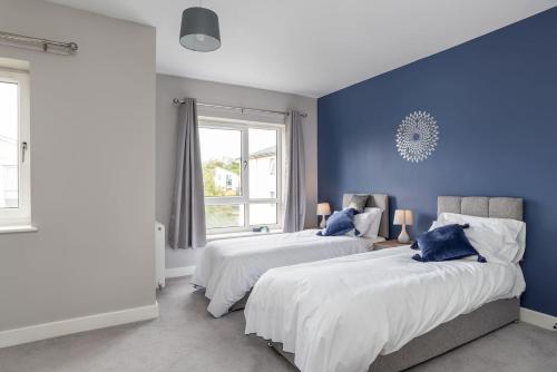two beds in a room with blue walls at Ashland House in Milton Keynes
