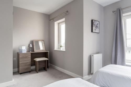 a white bedroom with a dresser and a mirror at Ashland House in Milton Keynes