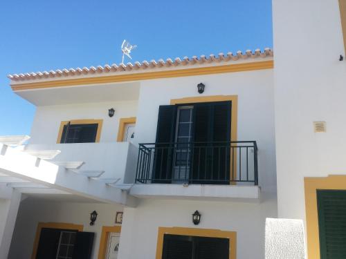 a white building with a balcony and a blue sky at Vivenda para férias (Algarve) in Manta Rota
