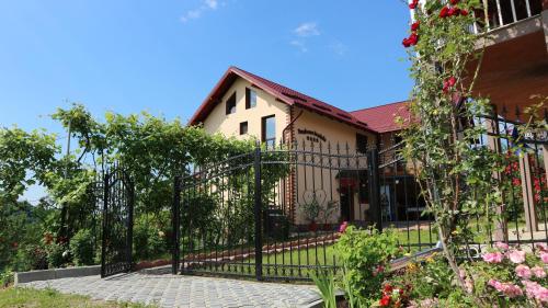 a black fence in front of a house with flowers at Pensiunea Luminita in Mustăţeşti