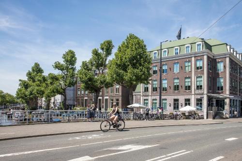 a woman riding a bike down a street next to a building at Boutique Hotel Notting Hill in Amsterdam