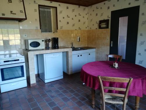 cocina con mesa y mantel púrpura en Maison à la ferme, en Saint-Aubin-le-Monial